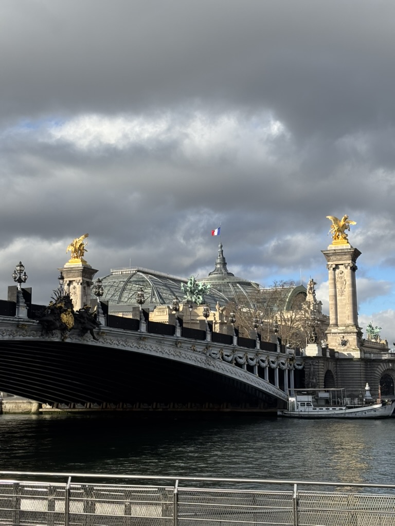 Tram passing a modern Paris building on a rainy street on March 26, 2026